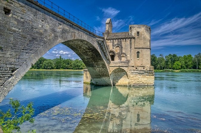 A stone arch of the old bridge and its small chapel, reflected in the still river
