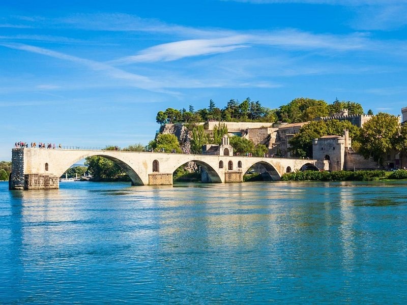The old bridge of Avignon stopping short in the middle of the blue Rhône, the walls behind