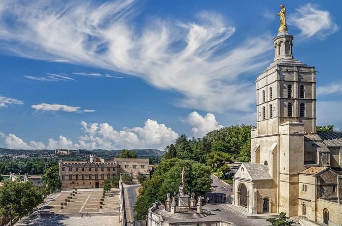 A cathedral belfry and its gilded statue above the square and the old town of Avignon