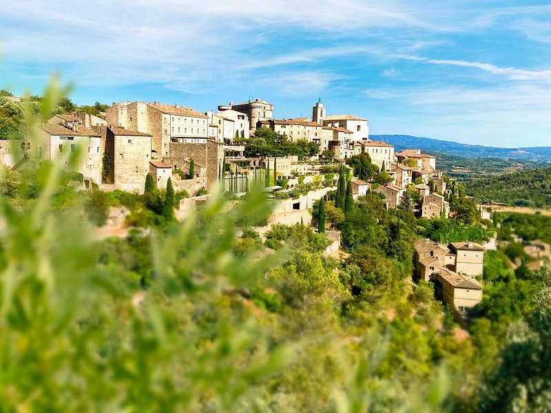 Gordes piled up its hillside above the Luberon valley, seen through the green of the slope