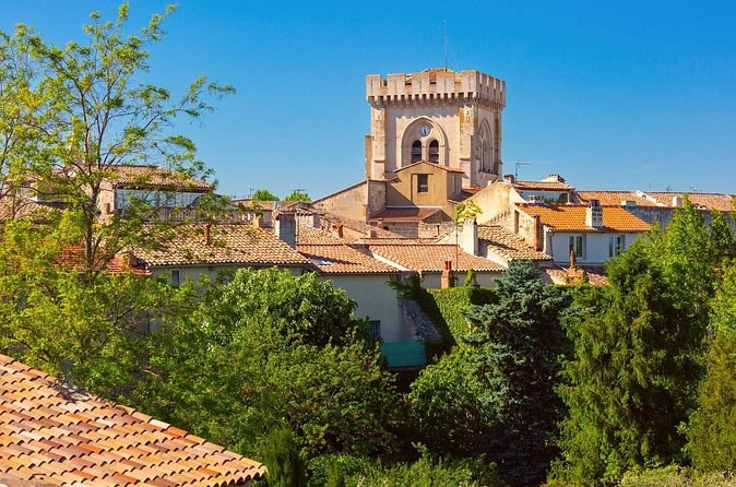 A square medieval tower above tiled roofs and trees