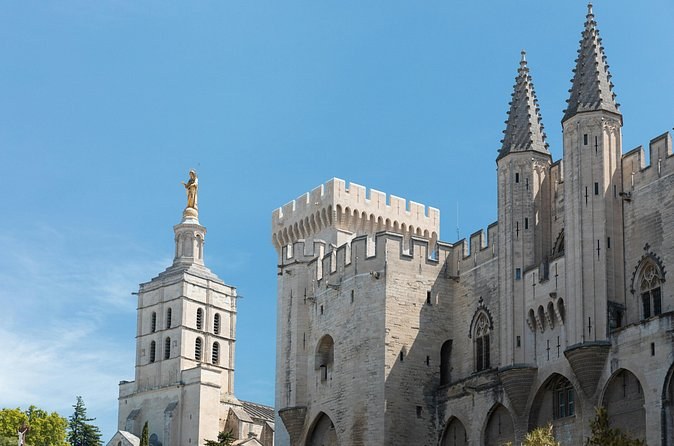 The Gothic towers of the popes' palace beside a belfry topped by a gilded statue